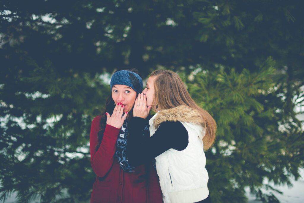 two girls are gossiping with funny expression